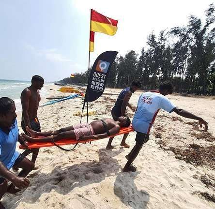 Beach lifeguards carrying a casualty on a stretcher beside the red and yellow flag