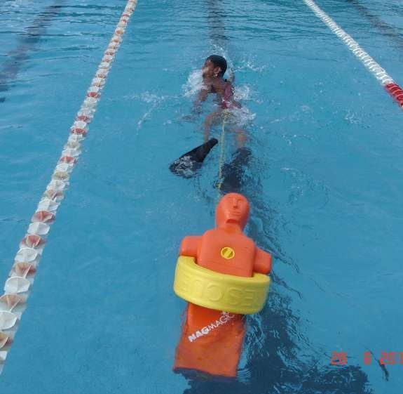 A swimmer towing a rescue manikin in a pool