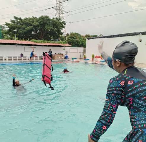 Instructor guiding a spinal board rescue in a pool